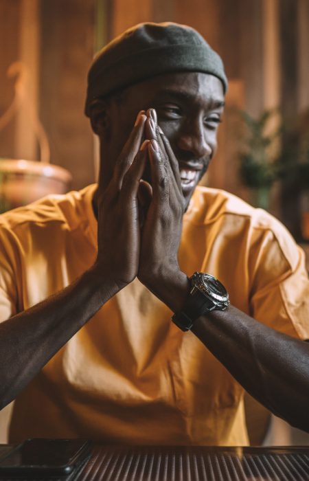 A young African American male smiling at dinner with his friends